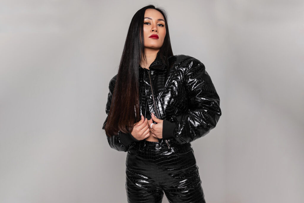 fashionable-beautiful-young-asian-girl-with-makeup-long-hair-fashionable-black-snake-skin-outfit-with-jacket-pants-poses-studio-against-gray-background edit